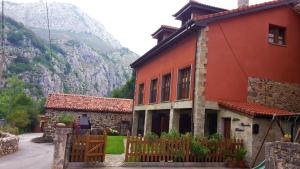 ein Haus mit einem Zaun vor einem Berg in der Unterkunft Apartamentos Blanca Senda del Oso in Páramo
