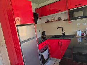 een keuken met rode kasten en een roestvrijstalen koelkast bij ptit coin hibiscus in Pointe-Noire