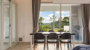 una sala da pranzo con tavolo e sedie e una grande finestra di Goseong Belloci Kids Poolivilla a Goseong