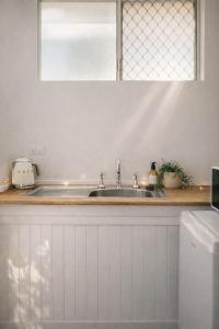 una cucina bianca con lavandino e finestra di Cooks Endeavour Motor Inn a Tweed Heads