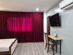 ein Schlafzimmer mit einem roten Vorhang und einem Schreibtisch in der Unterkunft Jewel's Hotel in Polomolok + 38 Fotos