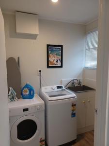 eine kleine Küche mit einer Waschmaschine und einem Waschbecken in der Unterkunft Cosy Cottage in Ruakaka