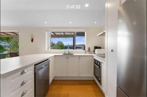 eine weiße Küche mit Spüle und Fenster in der Unterkunft Modern Lake View House in Mangakino