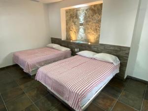2 Betten in einem Zimmer mit einer Wand in der Unterkunft Costa Ayala - Bungalow 5 with 2dbl beds and 1 sofa in Los Ayala
