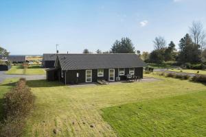una piccola casa nera con un ampio cortile di HA151-Hals-Kystvejen-38 a Hals