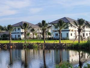 un bâtiment avec des palmiers devant un plan d'eau dans l'établissement Swiss Resort, à Ban Phe
