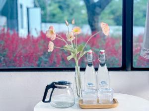 a table with two bottles and a vase with flowers at Mộc Châu House in Mộc Châu