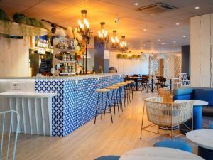 een restaurant met een bar met blauwe en witte tegels bij ibis Manosque Cadarache in Manosque