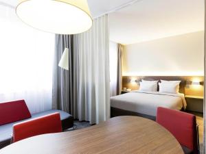een hotelkamer met een bed, een tafel en stoelen bij Novotel Suites Genève Aéroport in Genève