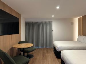 a hotel room with two beds and a table and a tv at Avero in Rotorua