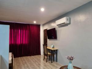 ein Wohnzimmer mit einem roten Vorhang und einem Tisch in der Unterkunft Jewel's Hotel in Polomolok