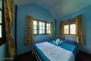ein blaues Schlafzimmer mit einem Bett und zwei Fenstern in der Unterkunft Blue Beach Bungalow in Bang Saphan Noi + 77 Fotos