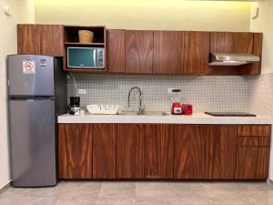 eine Küche mit Holzschränken und einem Edelstahlkühlschrank in der Unterkunft Penca Suites Valladolid in Valladolid