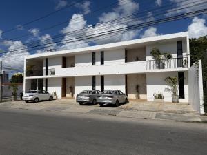 zwei Autos parkten vor einem weißen Gebäude in der Unterkunft Penca Suites Valladolid in Valladolid