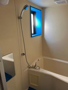 een badkamer met een bad en een raam bij Shinehouse2 in Kawaguchi