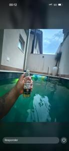 a person holding a bottle in a swimming pool at Casa bosque in São Paulo
