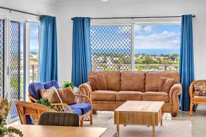 un soggiorno con divano e tende blu di Panoramic Oceanview Villa a Bowen