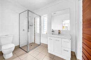 un bagno bianco con wc e doccia di Panoramic Oceanview Villa a Bowen