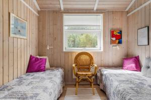 een slaapkamer met twee bedden en een stoel en een raam bij HA390-Saeby-Graevlingestien-5 in Grønsig