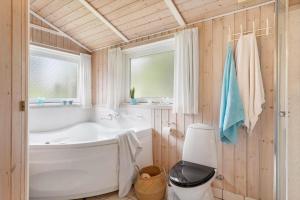 een badkamer met een bad, een toilet en een wastafel bij HA390-Saeby-Graevlingestien-5 in Grønsig +13 foto's