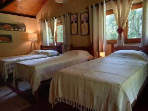 two beds in a room with two windows at Rio Privativo, Piscina e Starlink - Casa Terras de Minas in Gonçalves