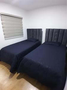 two beds sitting next to each other in a bedroom at Suite cerca de la UTPL y Centro Histórico in Loja