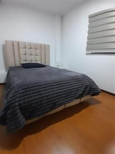 a bedroom with a bed with a black comforter at Suite cerca de la UTPL y Centro Histórico in Loja