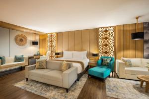 a hotel room with a bed and a couch and chairs at The Manohara Hotel Yogyakarta in Yogyakarta