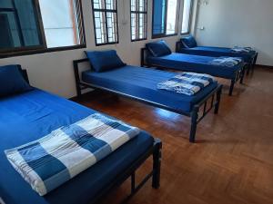 three blue beds in a room with windows at Doctor Thanut Hostel in Ubon Ratchathani