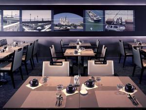 un restaurant avec des tables, des chaises et des photos sur le mur dans l'établissement Mercure Paris Ivry Quai De Seine, à Ivry-sur-Seine