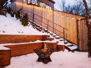 een met sneeuw bedekte trap met lampjes op een hek bij AlmaHouse Secluded Mountain Cabins in Alma-Ata