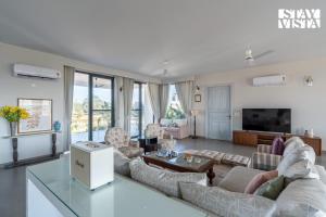 a living room with couches and a tv at StayVista at Treeansh with Pool, Lawn in Mohali