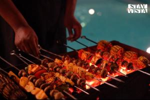 a person is cooking food on a grill at StayVista at Treeansh with Pool, Lawn in Mohali