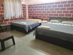 ein Zimmer mit zwei Betten und einer Ziegelwand in der Unterkunft Canara Highway Home Stay in Ankola