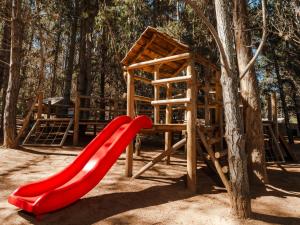 a playground with a red slide and a tree at Pao Pao Lodge Algarrobo in Algarrobo