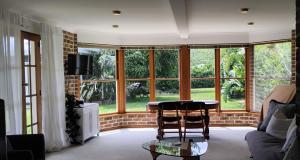een woonkamer met een tafel, stoelen en ramen bij River Dawn in Shoalhaven Heads
