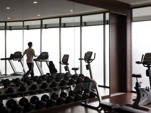 a man is walking in a gym with weights at Pullman Shanghai Xuhui in Shanghai