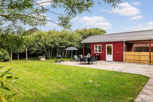 een rode schuur met een tafel en stoelen in een tuin bij 727-Thyboron-Magevej-10 in Thyborøn +23 foto's