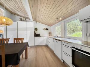 een keuken met witte kasten en een tafel en een raam bij 0001-Romo-Blabaervej-23 in Bolilmark +13 foto's