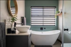 un bagno con una vasca bianca e un lavandino di Highland gate Golf estate Mountain view 780 a Dullstroom Altre 47 foto