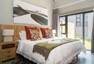 una camera da letto con un grande letto bianco con cuscini arancioni di Highland gate Golf estate Mountain view 780 a Dullstroom