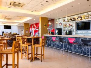 ein Restaurant mit einer Bar mit Holztischen und -stühlen in der Unterkunft ibis Ourinhos in Ourinhos