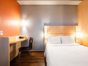 a hotel room with a bed and a desk at ibis Ourinhos in Ourinhos