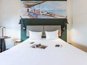 een slaapkamer met een groot wit bed en een schilderij bij Hotel Ibis Lisboa Parque das Nações in Lissabon +78 foto's