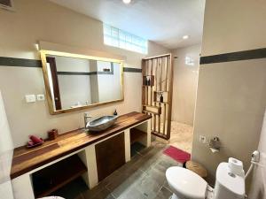 a bathroom with a sink and a toilet and a mirror at Mango Selong in Selong Belanak