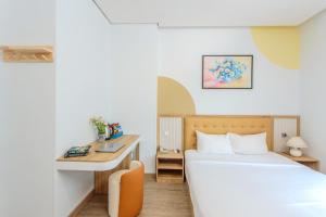 een kleine slaapkamer met een bed en een bureau bij Palmier Hotel - Art House Da Nang in Da Nang +65 foto's