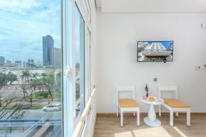 a white room with a table and chairs and a window at Palmier Hotel - Art House Da Nang in Danang