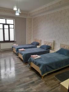a room with four beds with blue sheets on them at Butik in Ganja