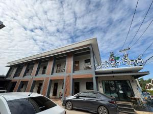 Une voiture garée devant un bâtiment avec un bateau sur le toit dans l'établissement โรงแรมพณิชาวิลล์, à Ban Sok Pho