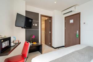 a bedroom with a bed and a red chair and a television at Life The One Makassar in Makassar +8 photos